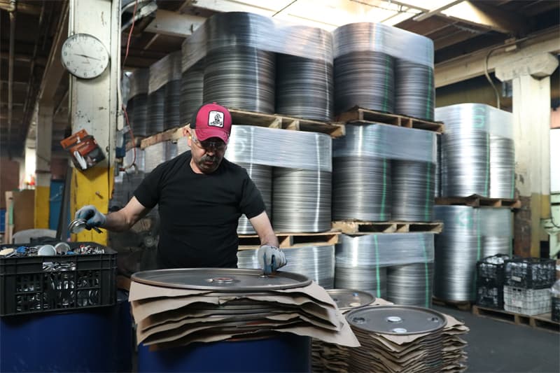 A worker in the North Coast Container facility stacking 55-gallon drum lids and liners